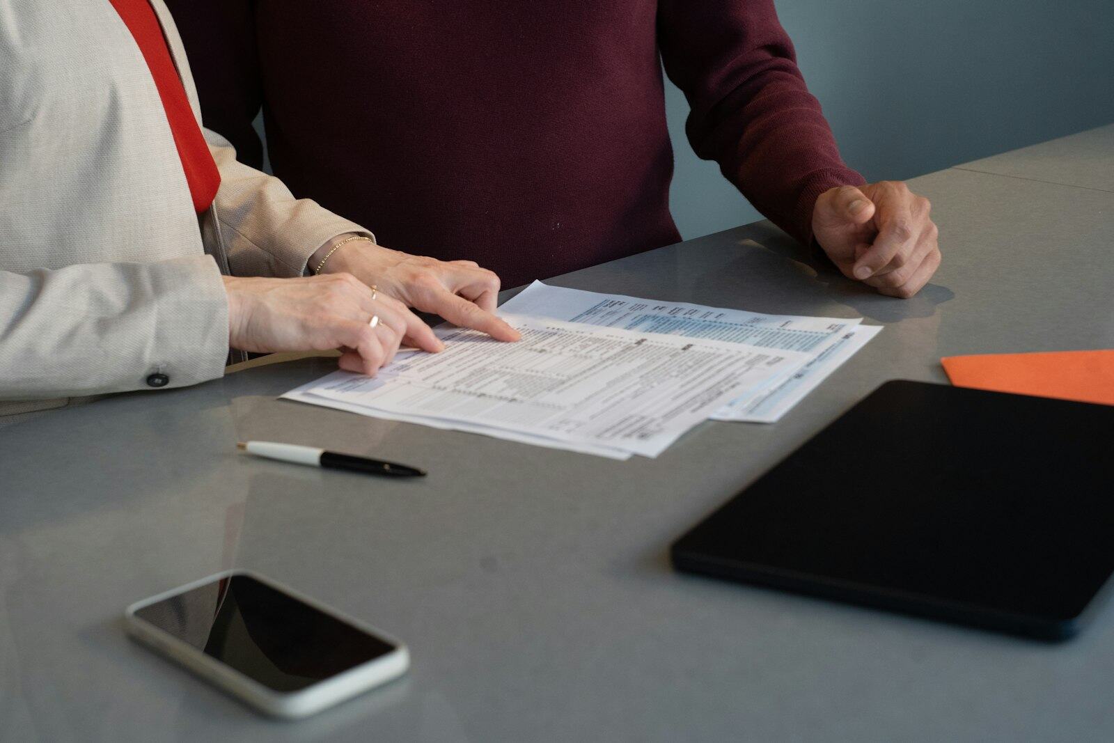 Deux personnes examinent des documents administratifs autour d'une table